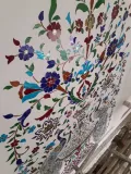 Intricate colored stained glass inlay work on a wall, showcasing traditional floral craftsmanship